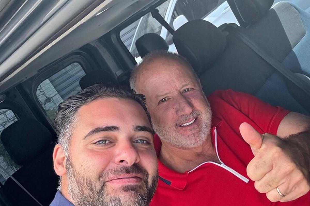 Δύο άντρες κάθονται σε ένα αυτοκίνητο κάνοντας ένα χαιρετισμό