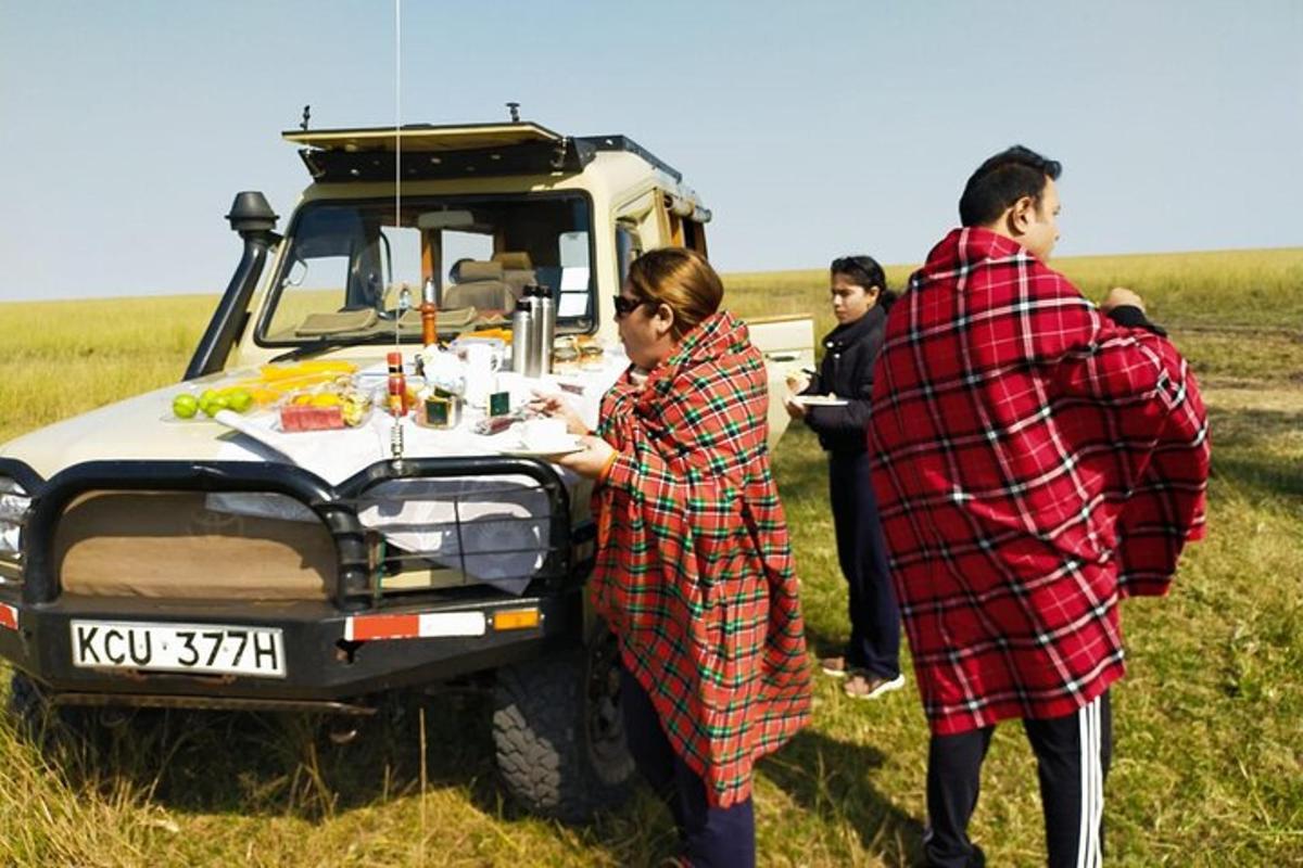 un gruppo di persone in piedi attorno a un tavolo accanto a un veicolo