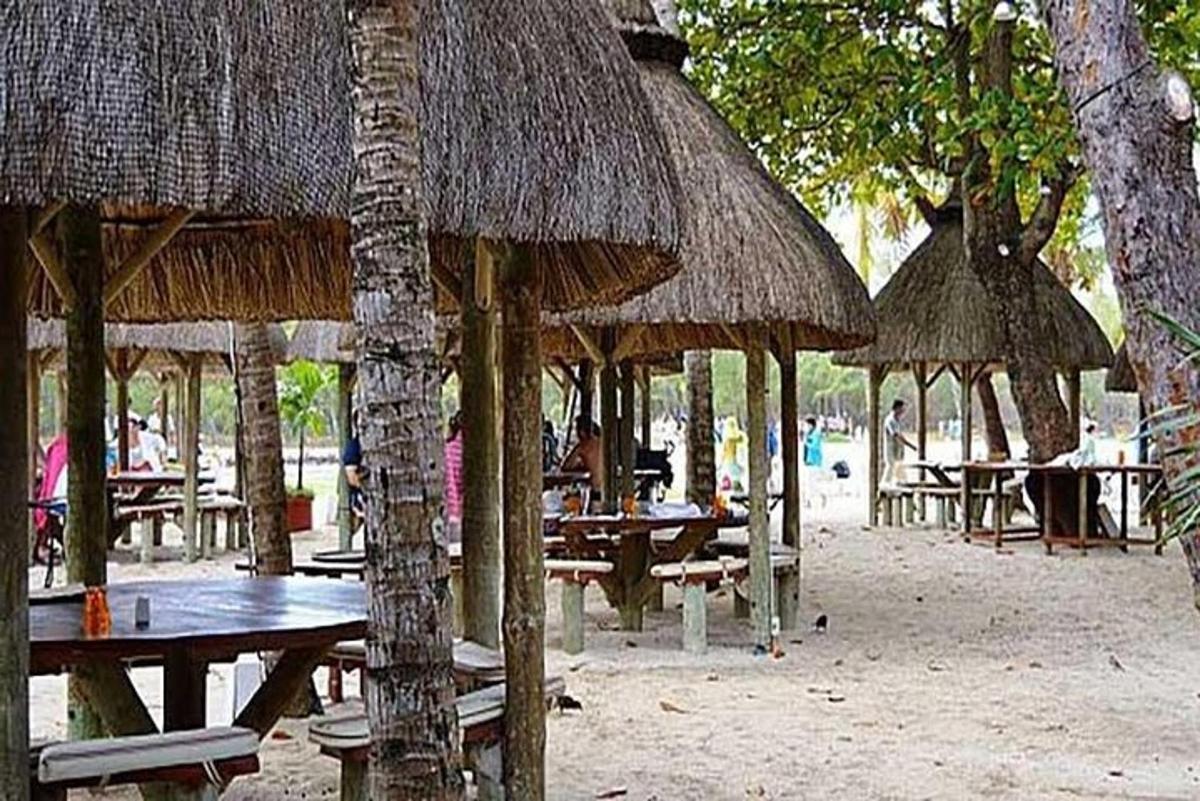isang grupo ng mga mesa at dayami na payong sa isang dalampasigan