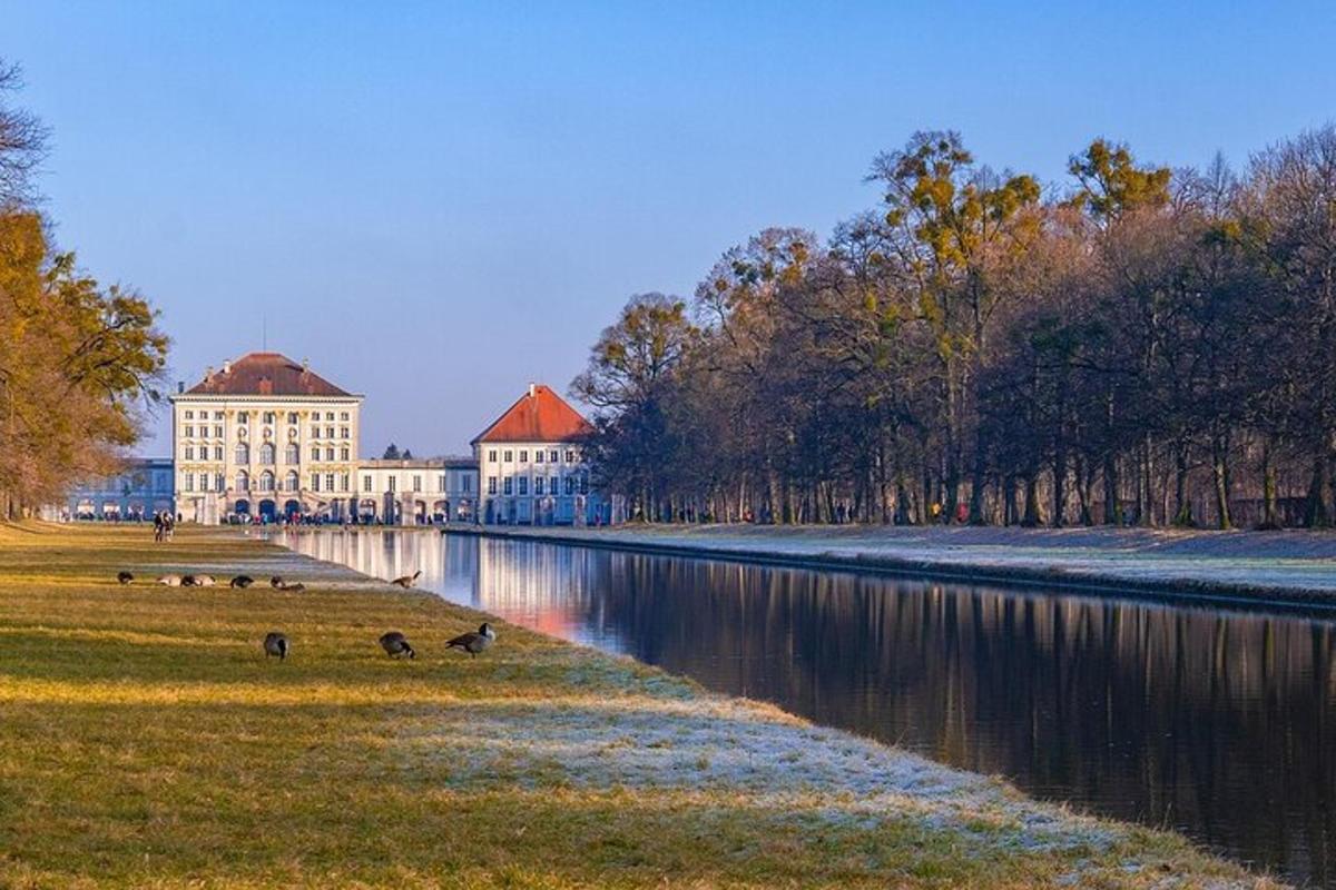 Un edificio al lado de un río con patos en el césped.