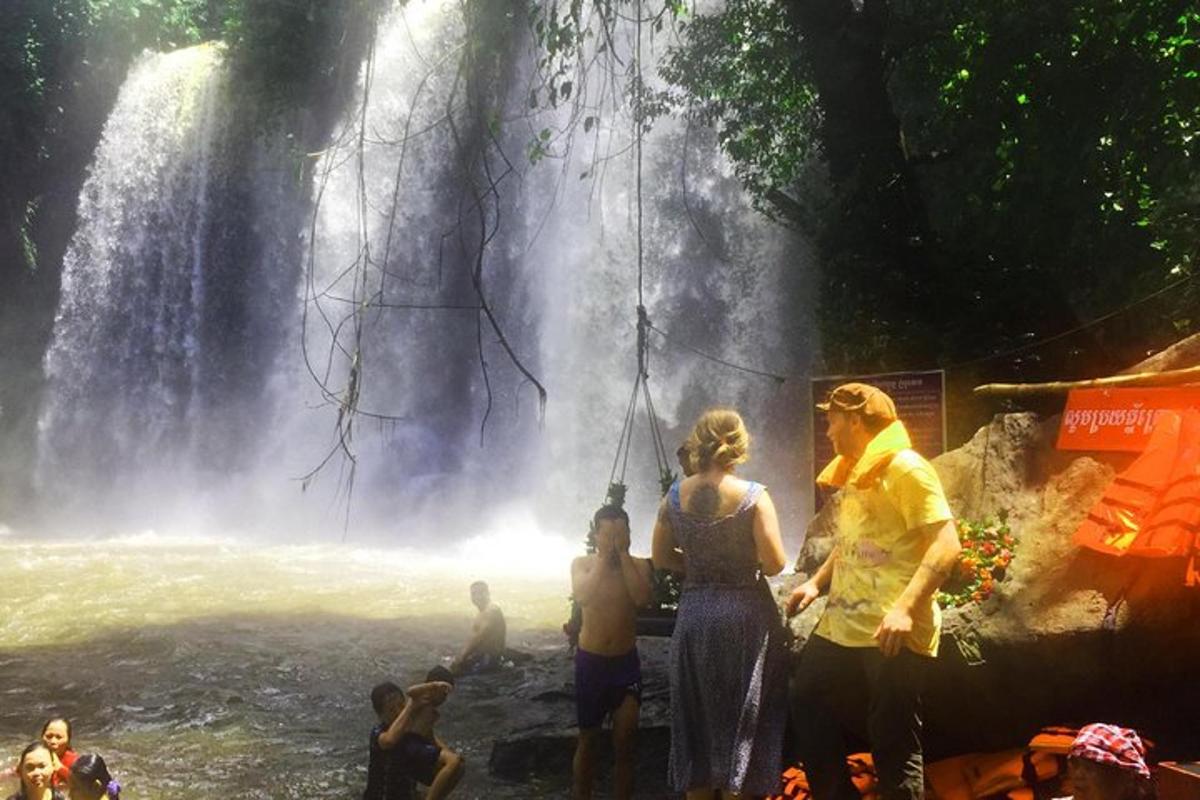 um grupo de pessoas em pé em frente a uma cachoeira