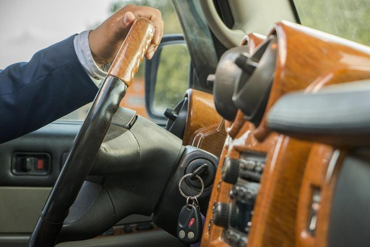 un uomo alla guida di un'auto con un volante di legno