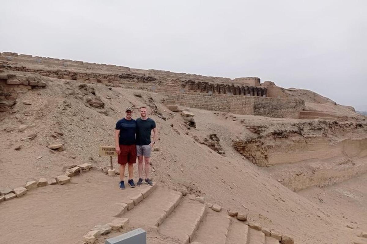Dos hombres están parados frente a unas ruinas.