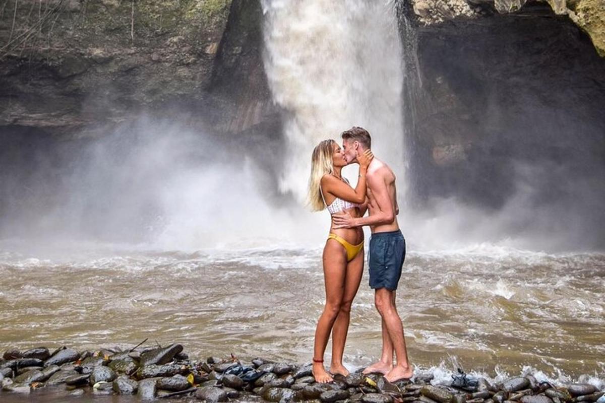 Un hombre y una mujer de pie frente a una cascada