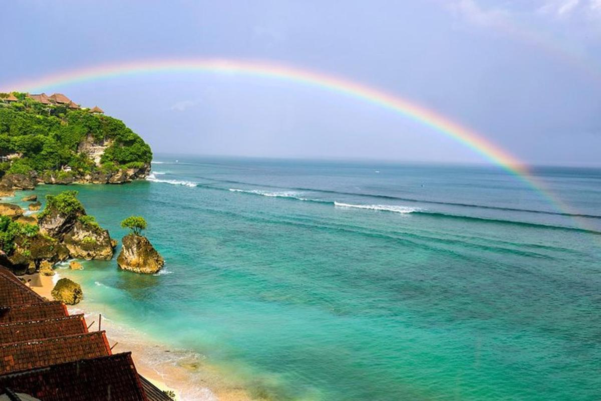 a rainbow over the ocean with a beach