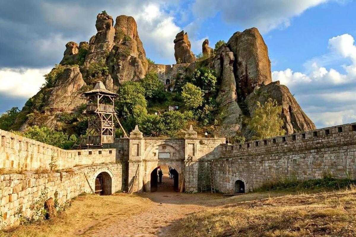 Un edificio de piedra con una montaña al fondo.