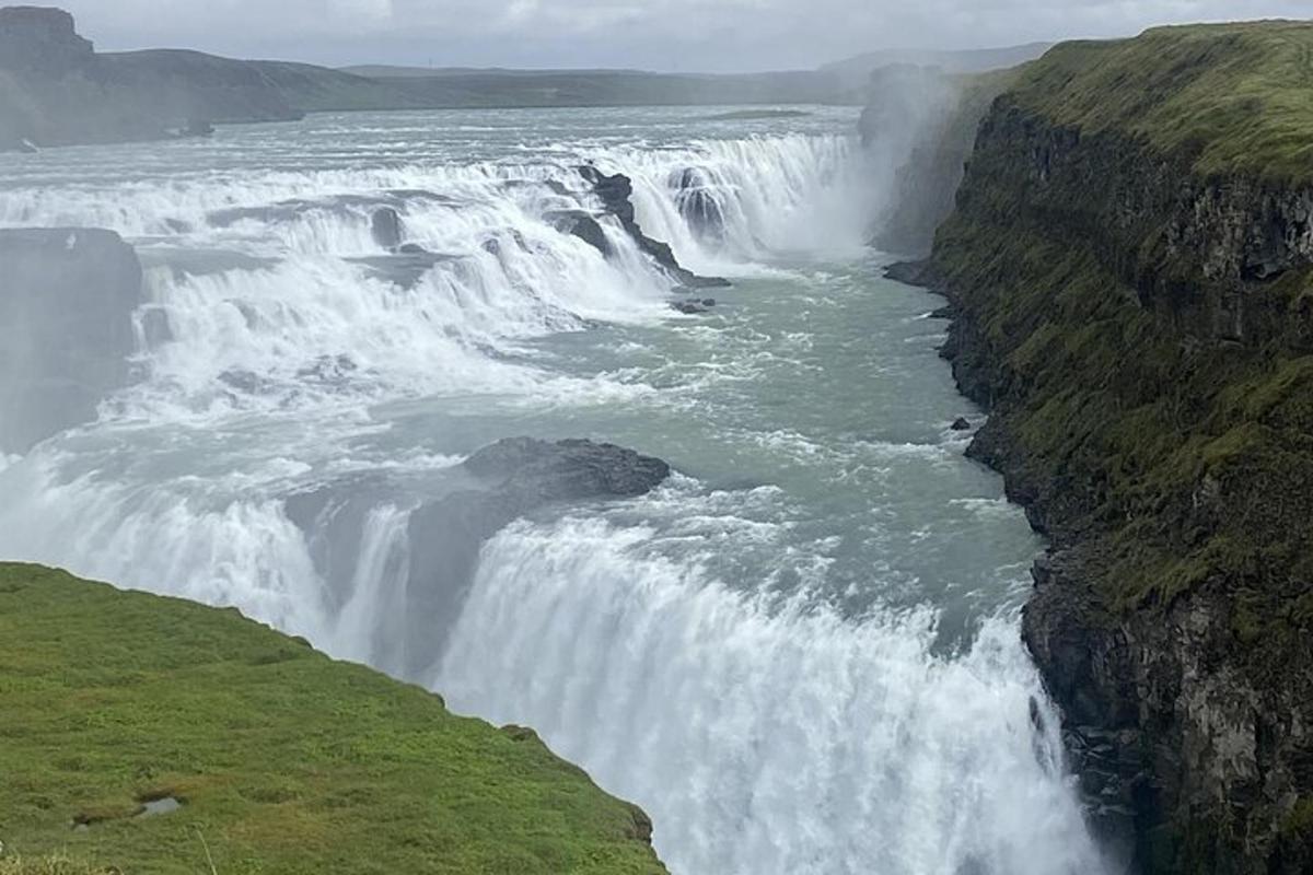 en foss på siden av en klippe ved siden av en elv