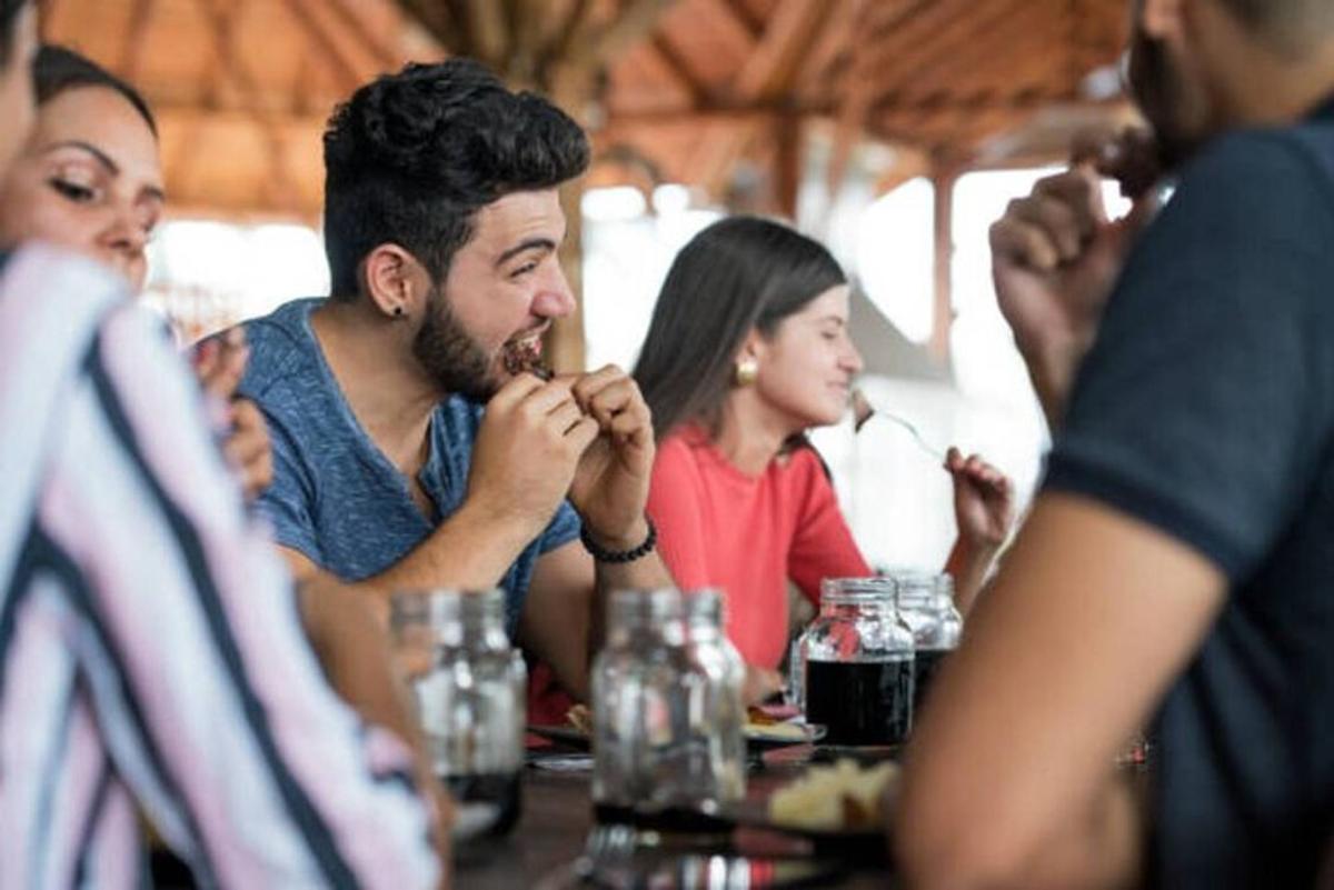 Un grupo de personas sentadas en una mesa comiendo comida