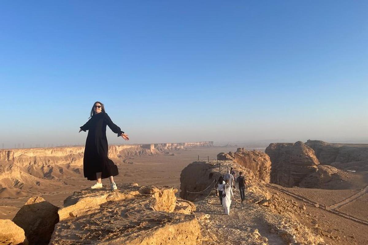 una donna in piedi in cima a una scogliera nel deserto