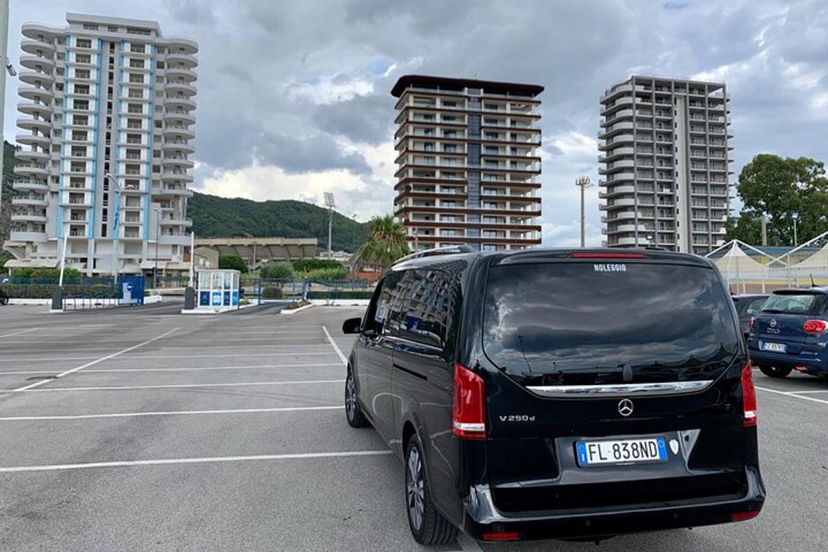 Černá dodávka zaparkovaná na parkovišti s vysokými budovami
