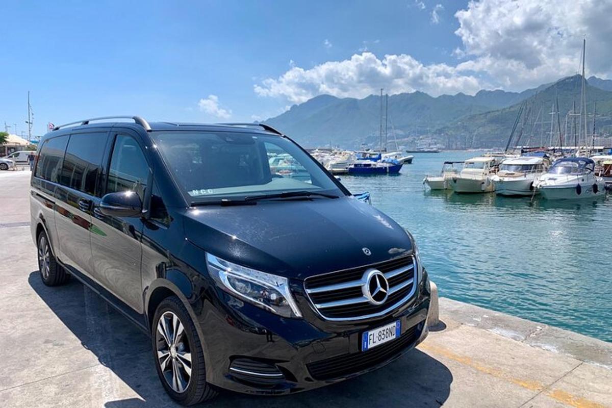 sininen Mercedes-Benz-pakettiauto pysäköitynä venesataman viereen