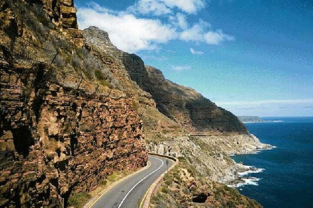a road on the side of a mountain next to the ocean