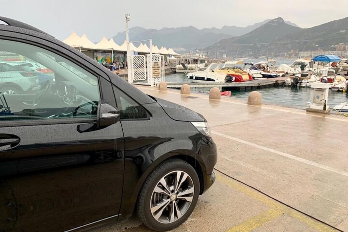 un cotxe negre aparcat al costat d'un port esportiu amb vaixells