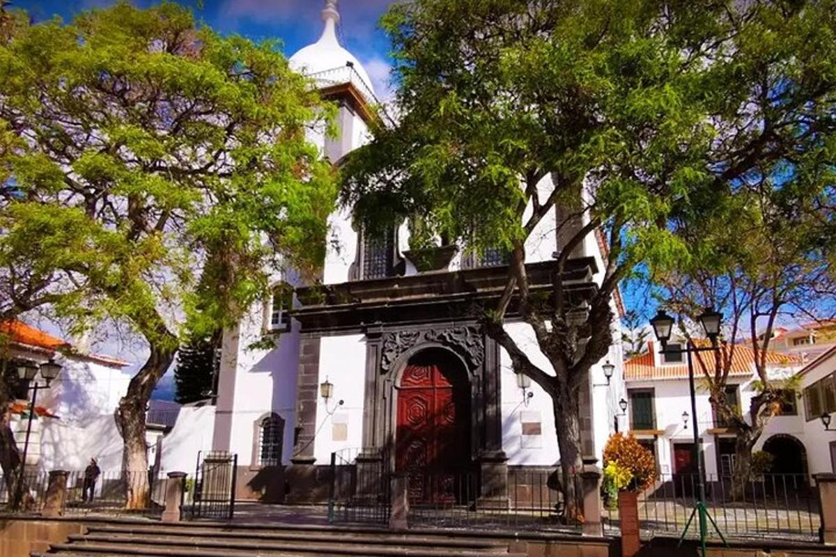 a white church with a red door and trees