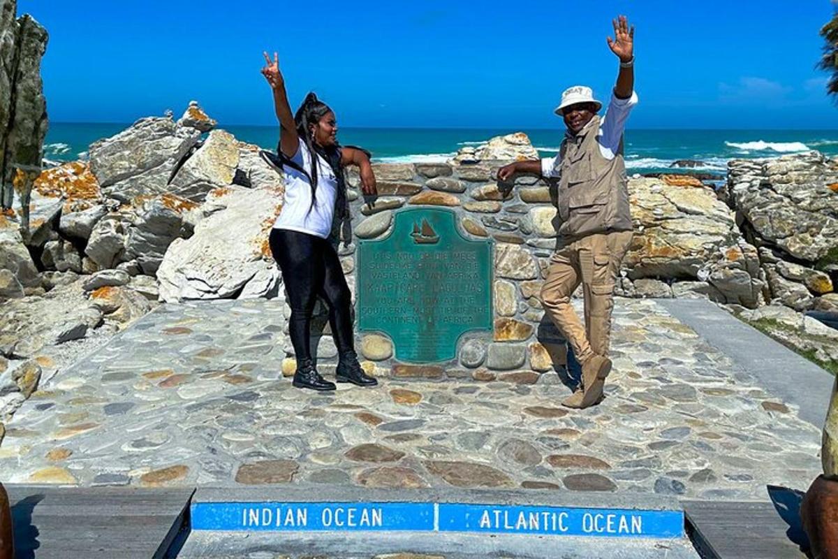 two people standing in front of a sign at the ocean
