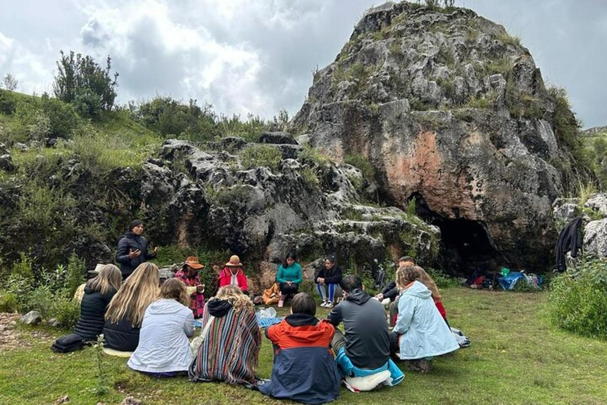 skupina ljudi, ki sedijo na travi pred skalno formacijo
