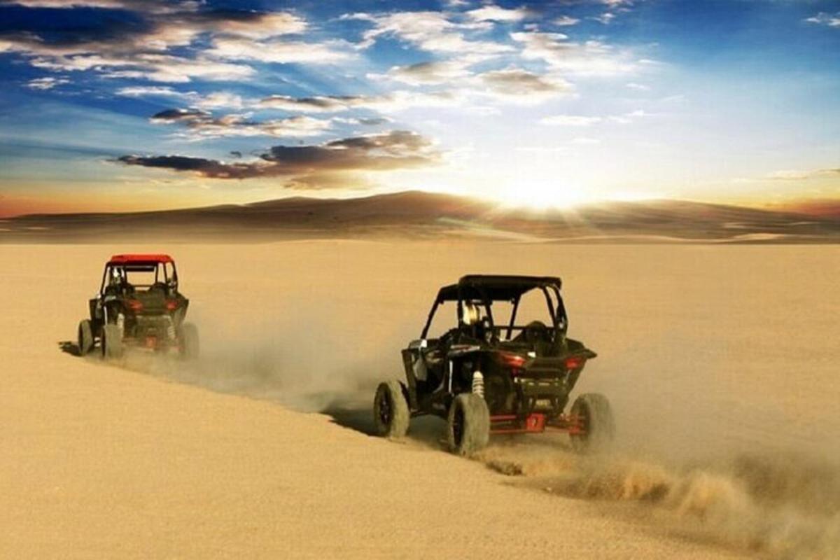 twee ATV's rijden door het zand in de woestijn