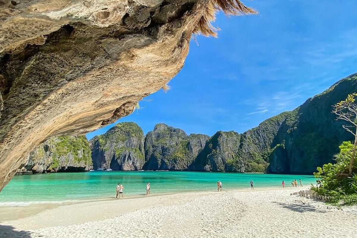 กลุ่มคนกำลังเดินเล่นอยู่บนชายหาดใกล้ถ้ำ