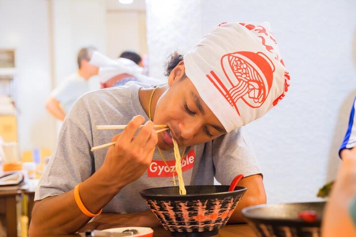 a man eating a bowl of noodles with chopsticks