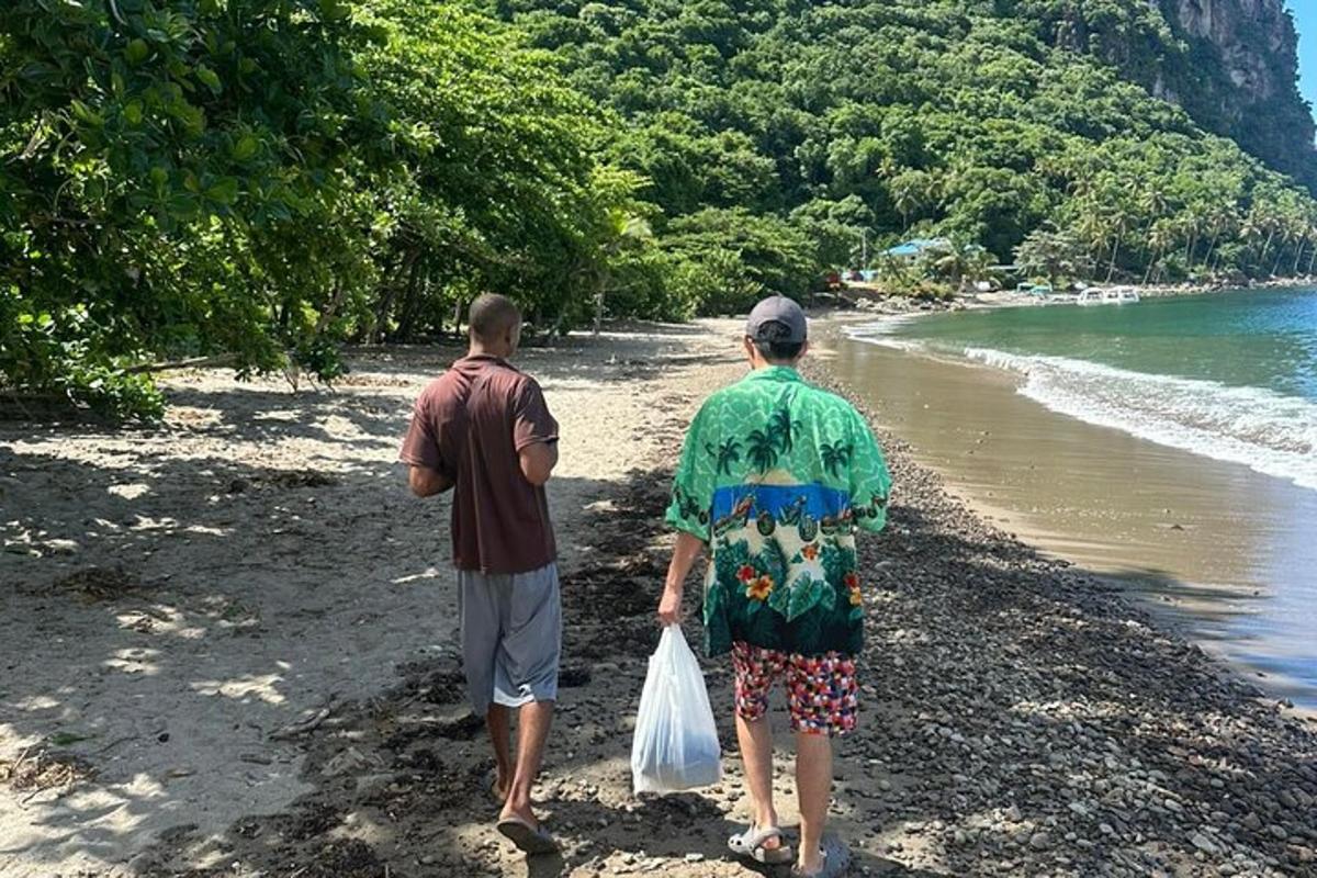 two men walking on the beach with a bag