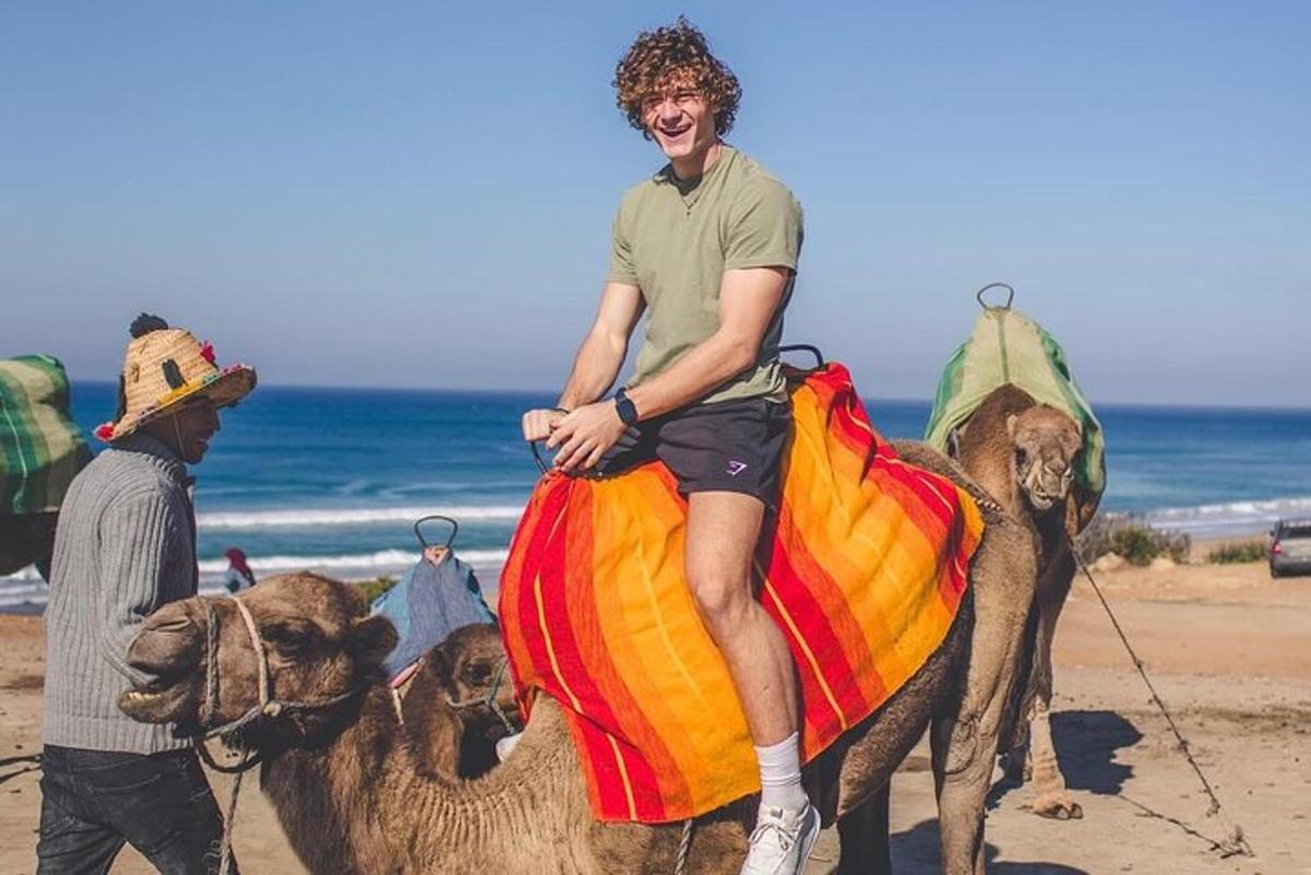 un hombre montando un camello en la playa