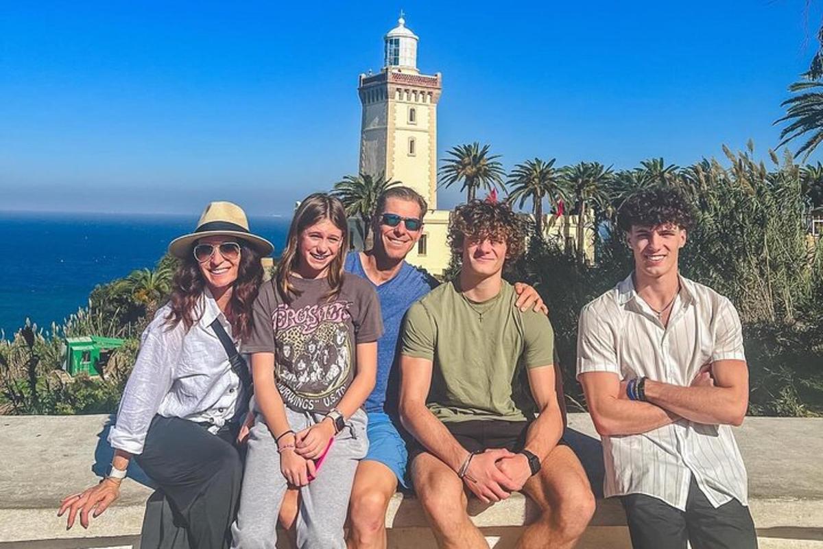 eine Gruppe von Menschen posiert vor einem Leuchtturm