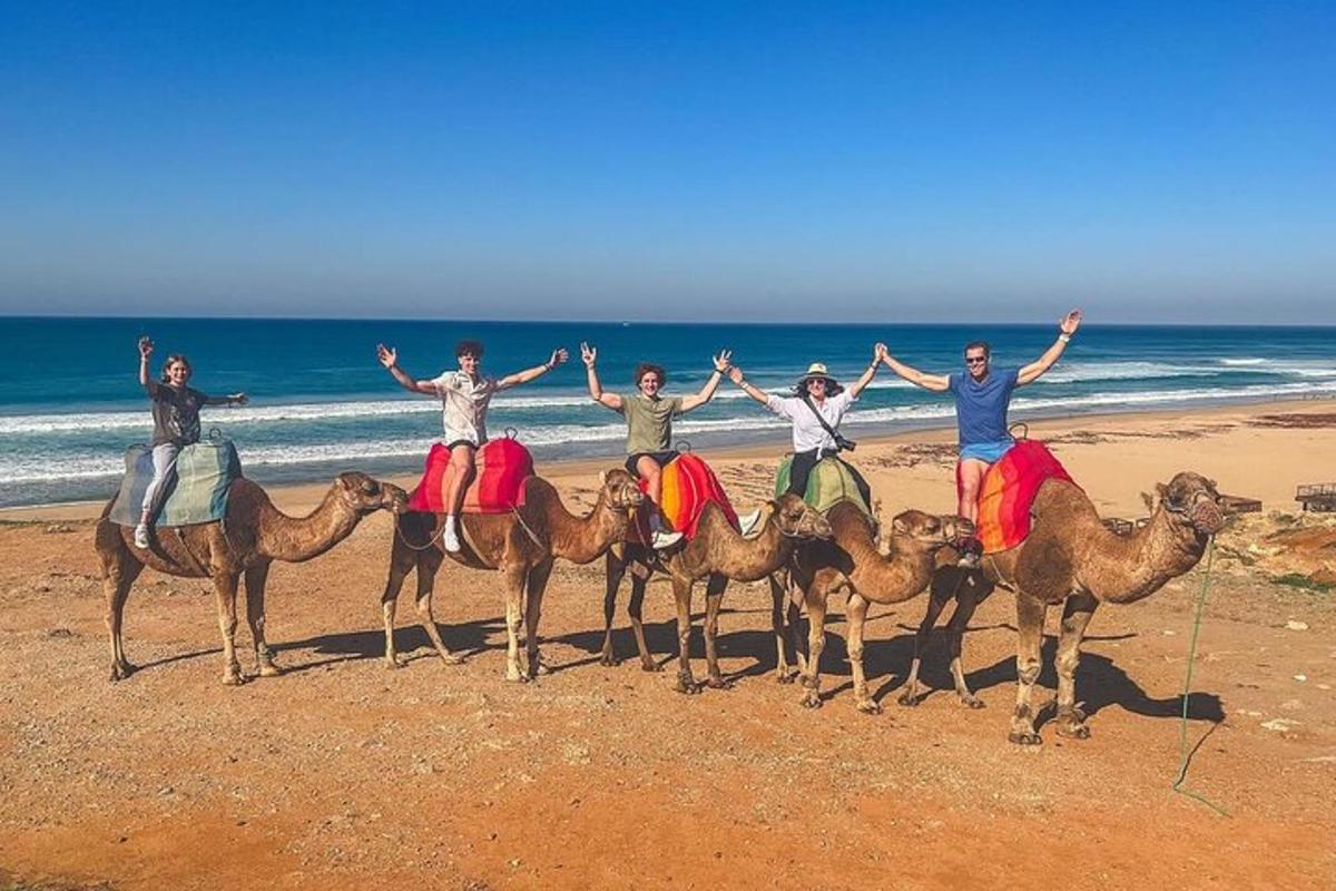 eine Gruppe von Menschen auf Kamelen am Strand