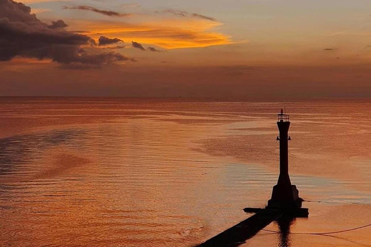 a lighthouse on the shore of the ocean at sunset
