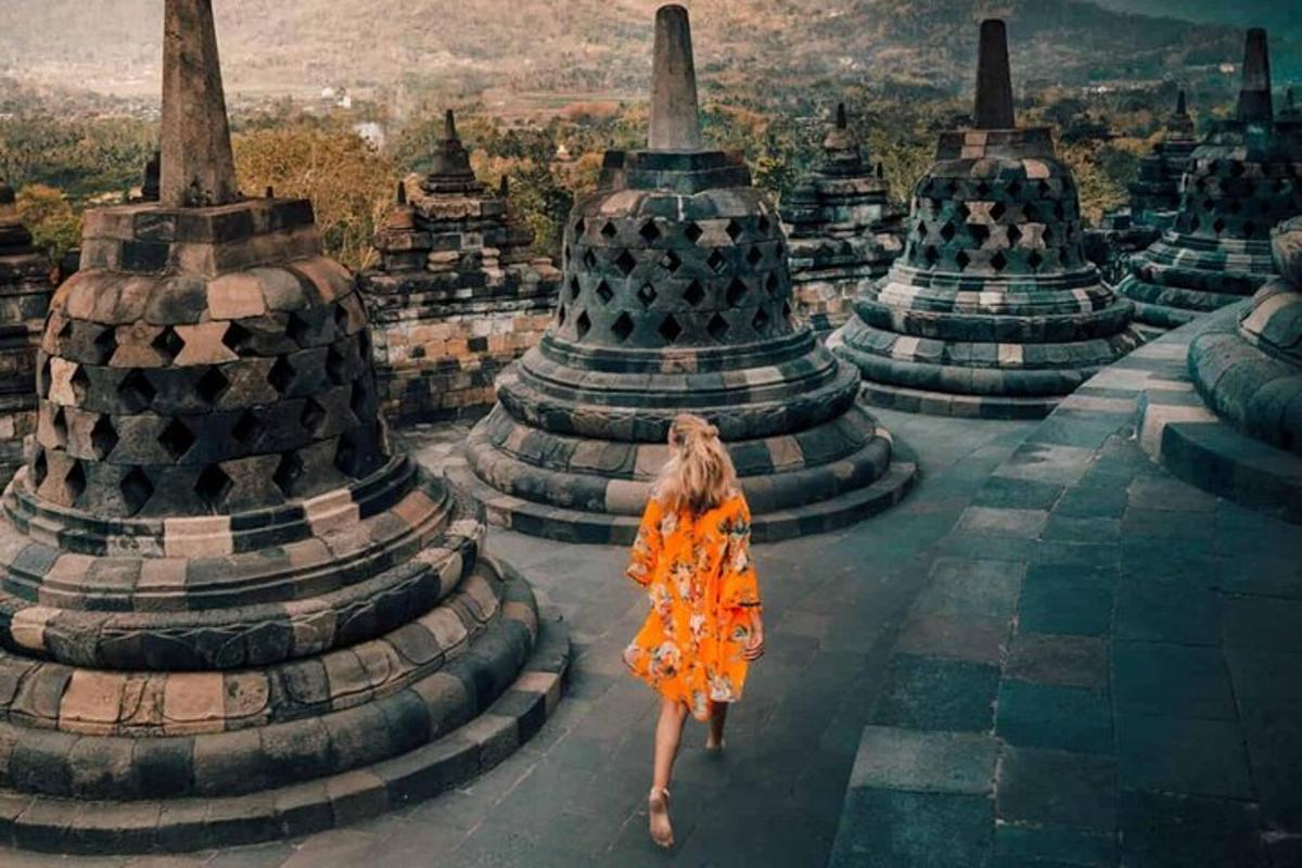 eine Frau in einem orangefarbenen Kleid, die auf einem Tempel geht