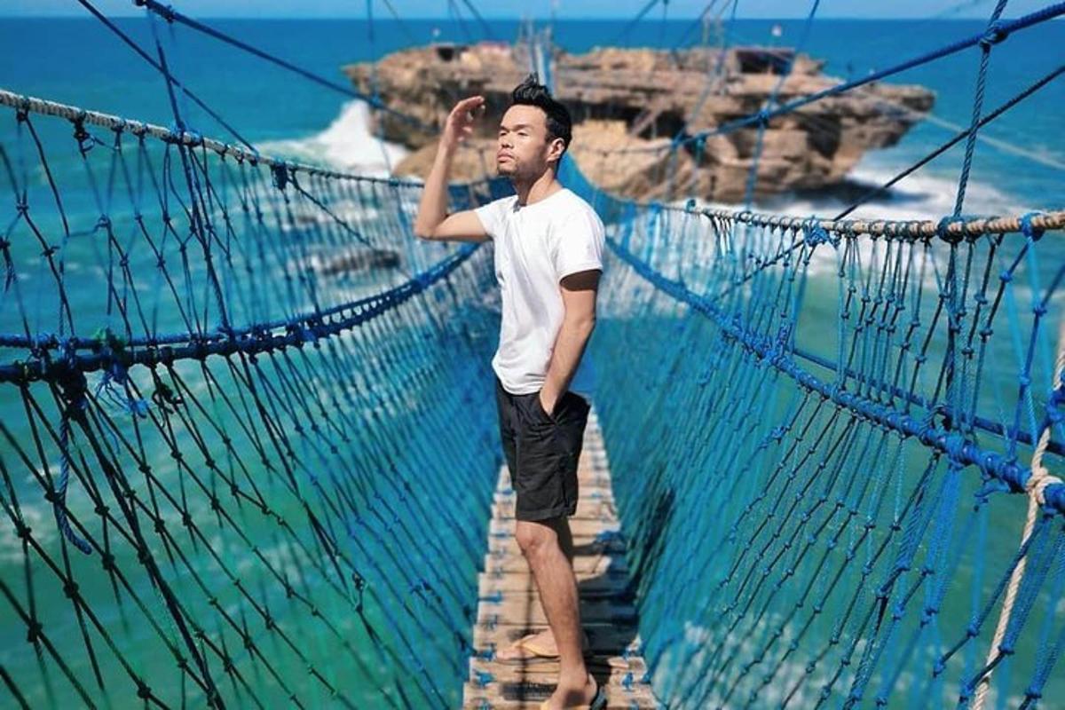 a man standing on a suspension bridge over the ocean