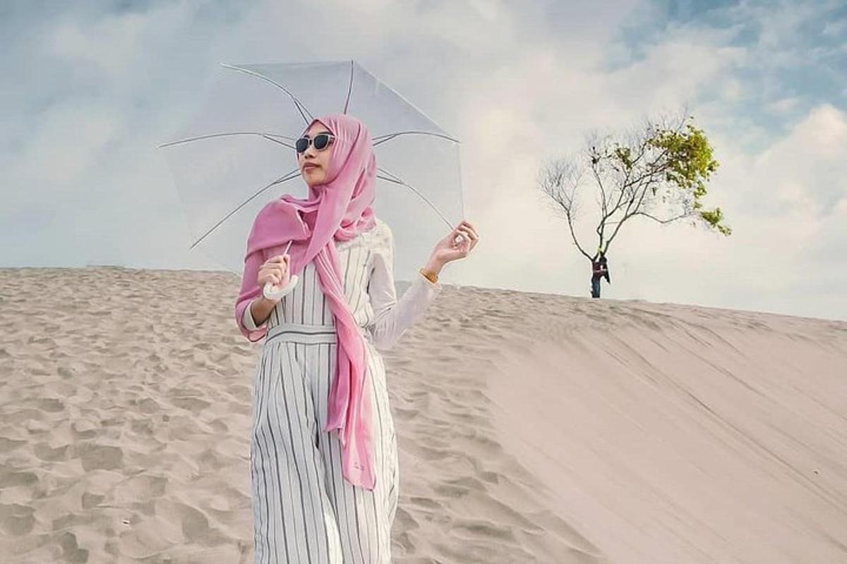 a woman standing on the beach holding an umbrella