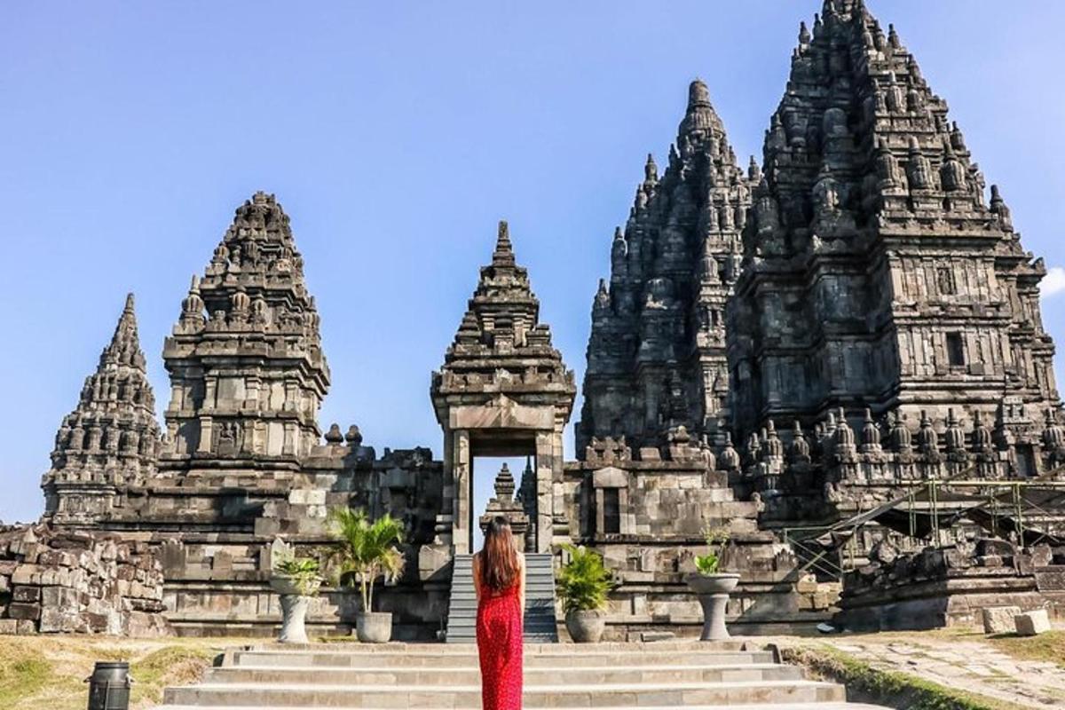 a woman in a red dress standing in front of a temple