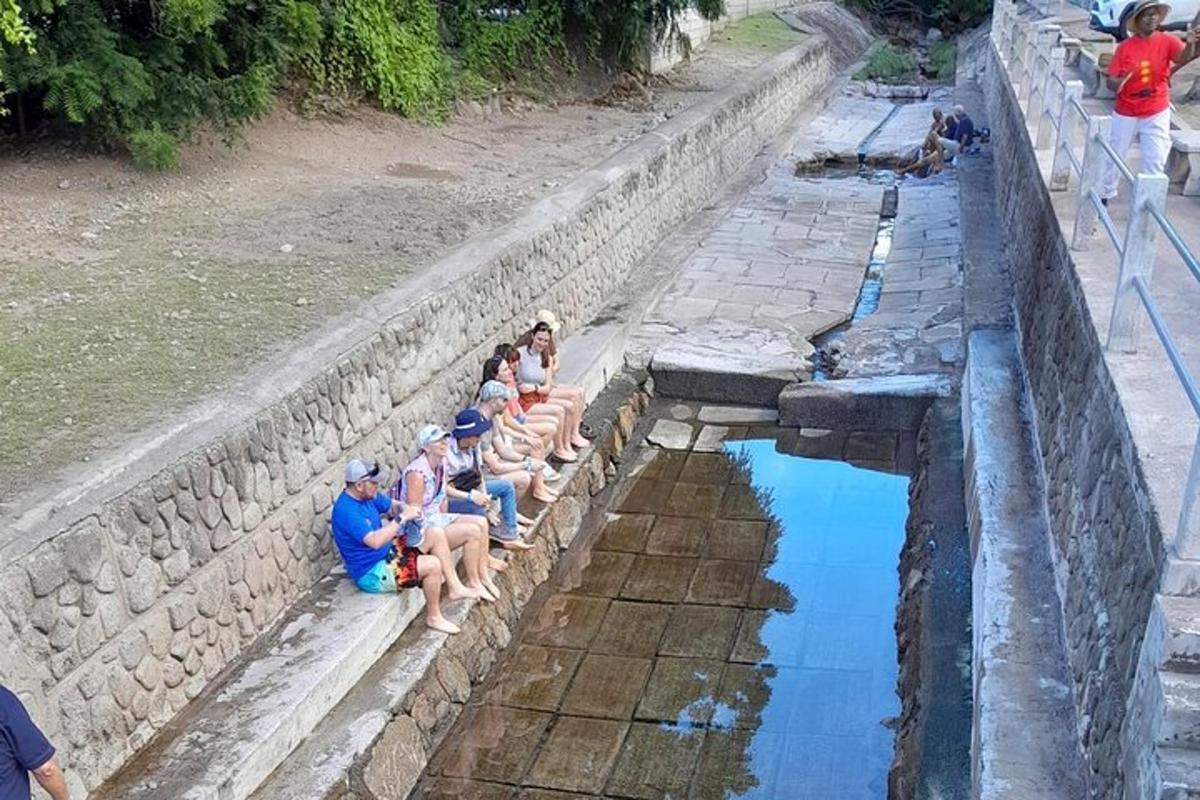 a group of people sitting on a wall near a pool of water