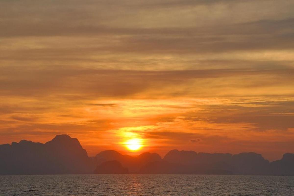 un tramonto sull'oceano con le montagne sullo sfondo