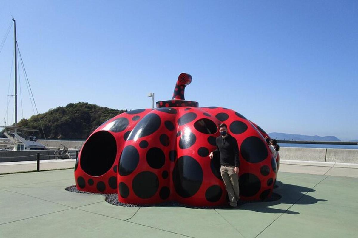 a man standing next to a giant lady bug statue