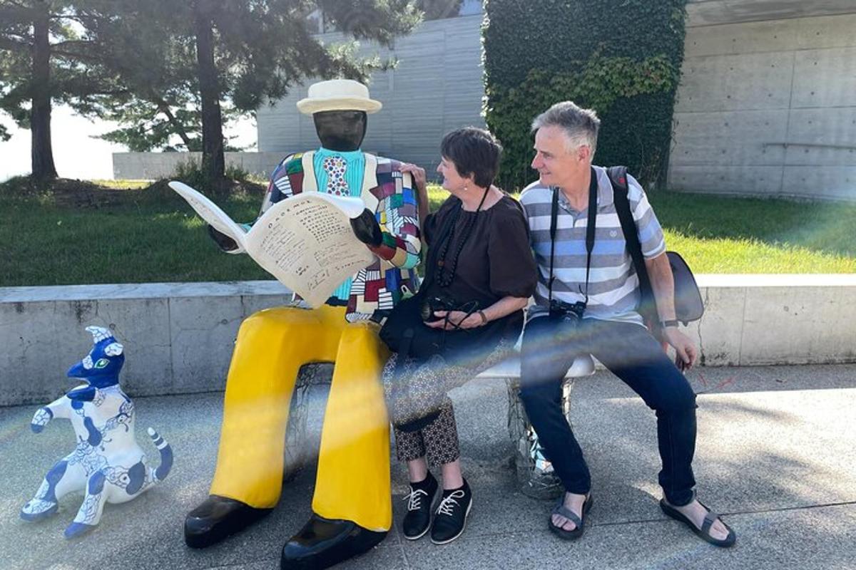 a man and a woman sitting on a bench with a statue