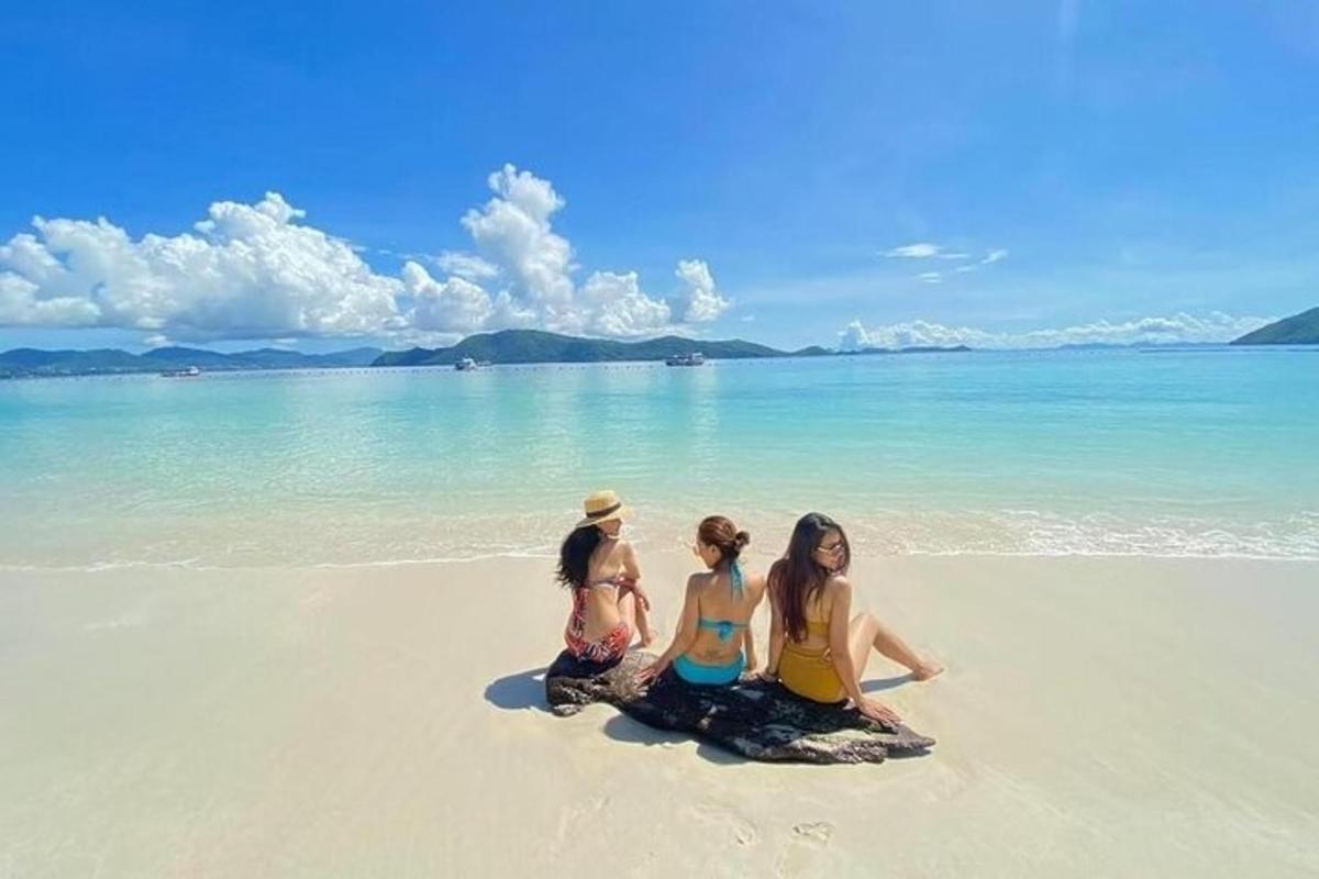 tre jenter som sitter på en strand i vannet