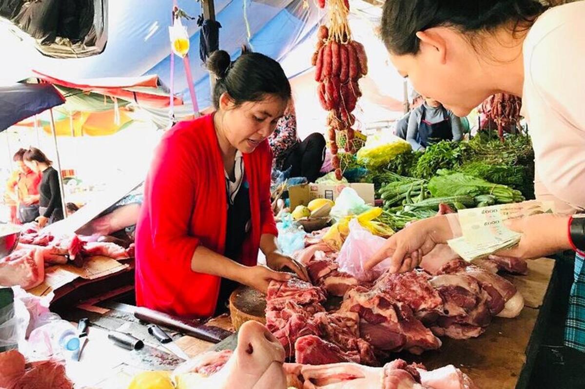 a woman is buying meat at a market