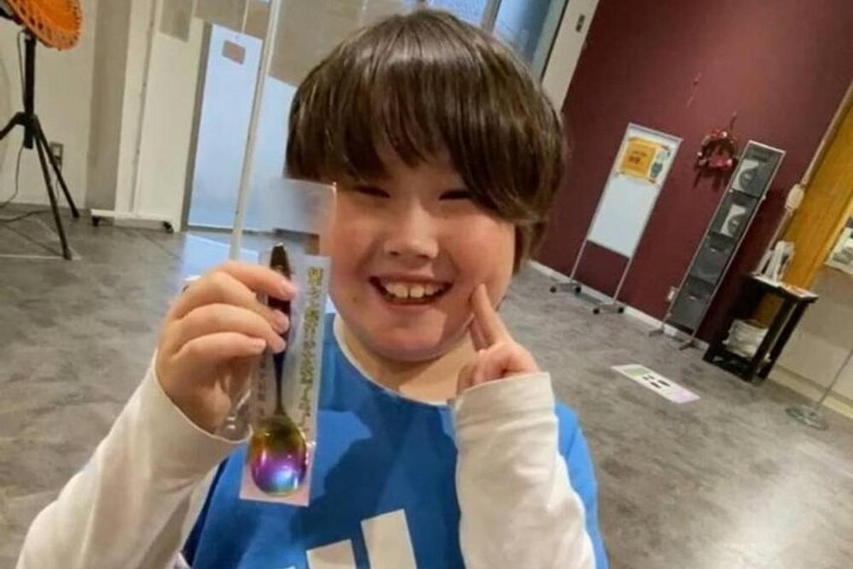 a young boy holding up a bottle with his fingers