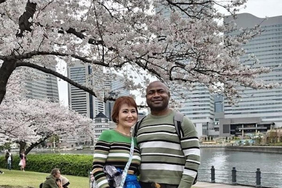 Un hombre y una mujer de pie bajo un árbol con flores.