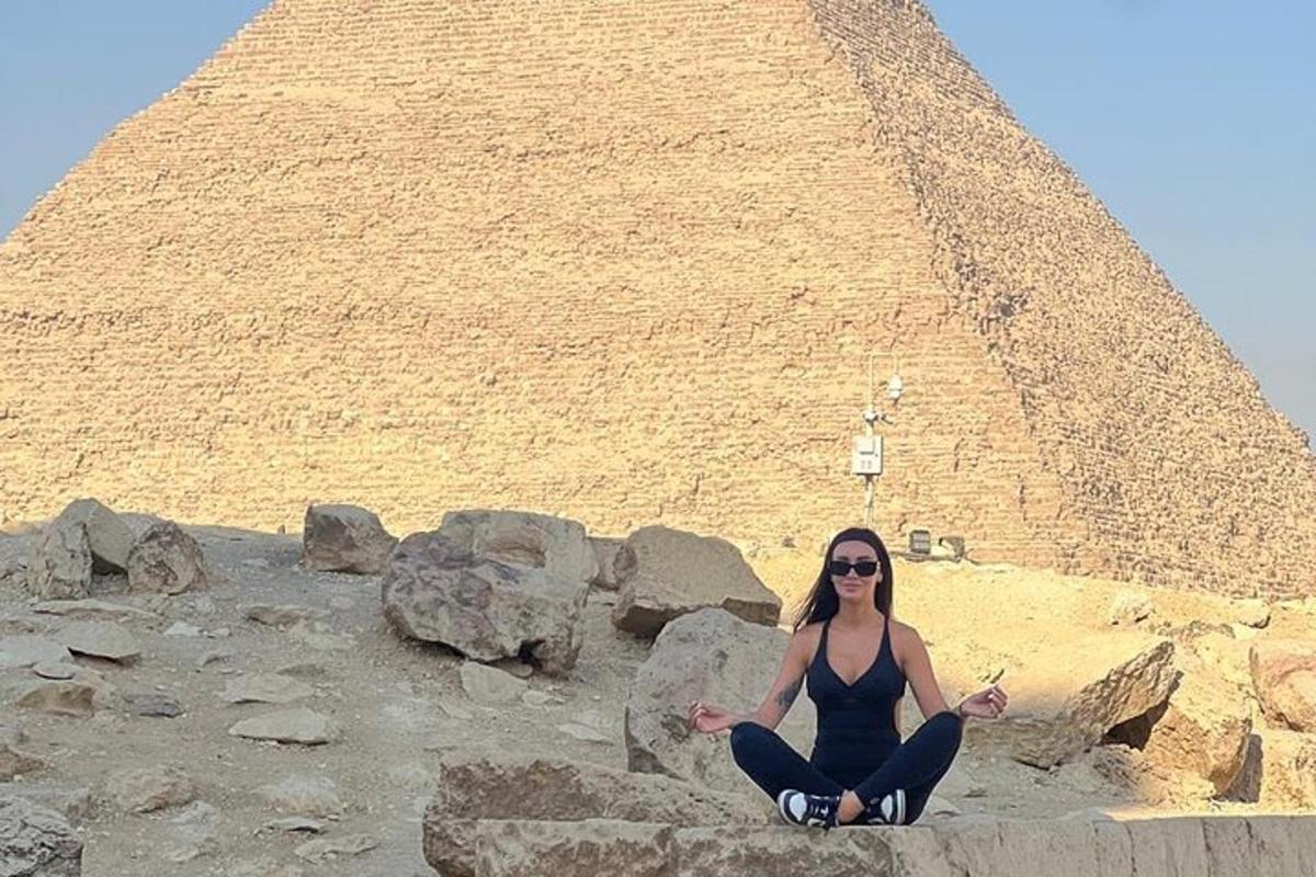 žena sedící na skalách před pyramidou
