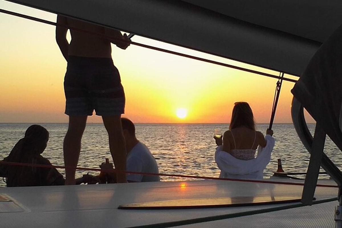 Un grupo de personas sentadas en un barco mirando la puesta de sol