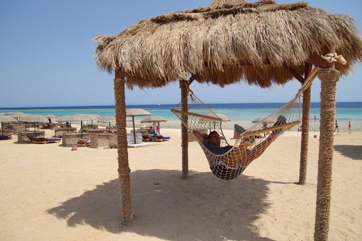 una donna sdraiata su un'amaca sotto un ombrellone di paglia sulla spiaggia