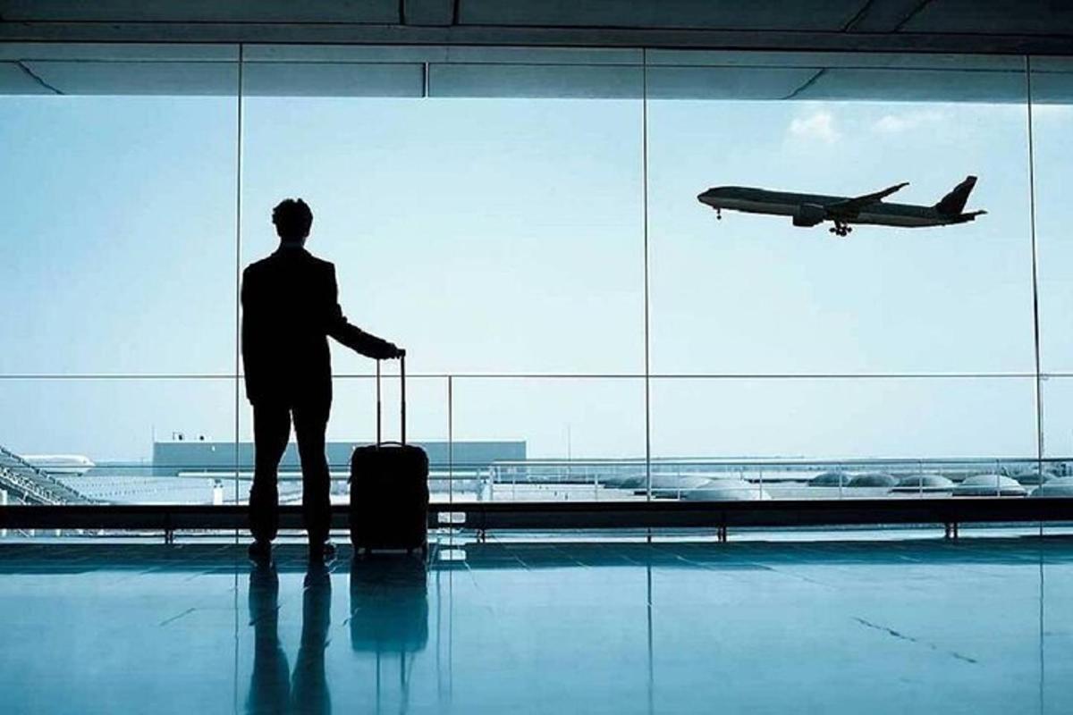 muž stojící na letišti a dívající se na letadlo