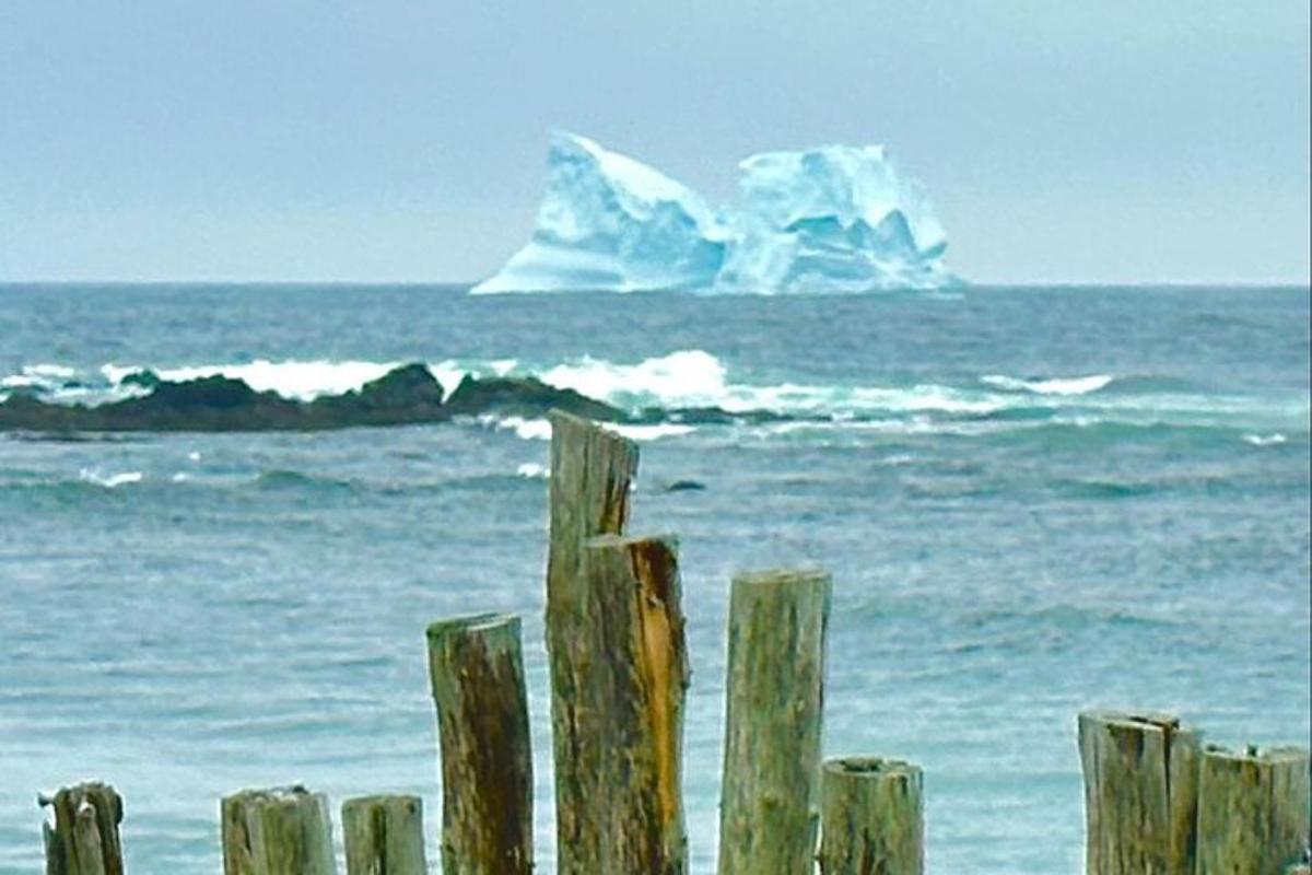an iceberg in the ocean next to a wooden fence