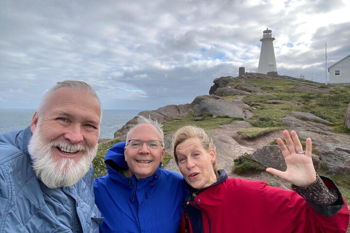 a group of three people standing in front of a lighthouse