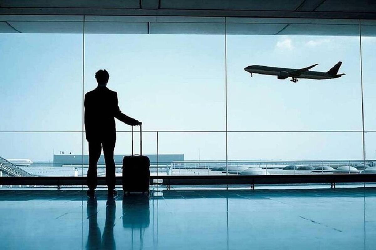 muž stojící na letišti a dívající se na letadlo