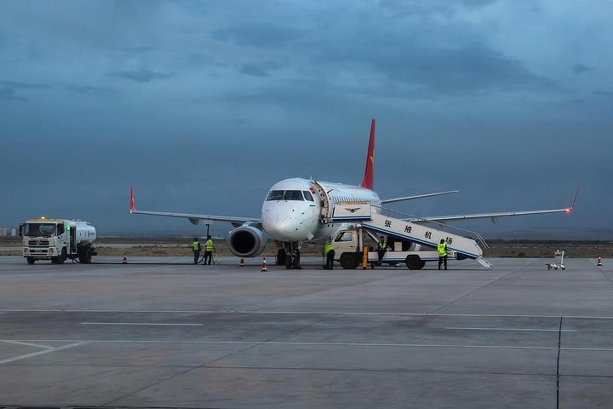 a plane sitting on the runway with people standing around it