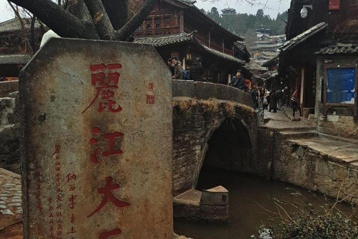 eine Steinbrücke über einen Fluss in einem Dorf
