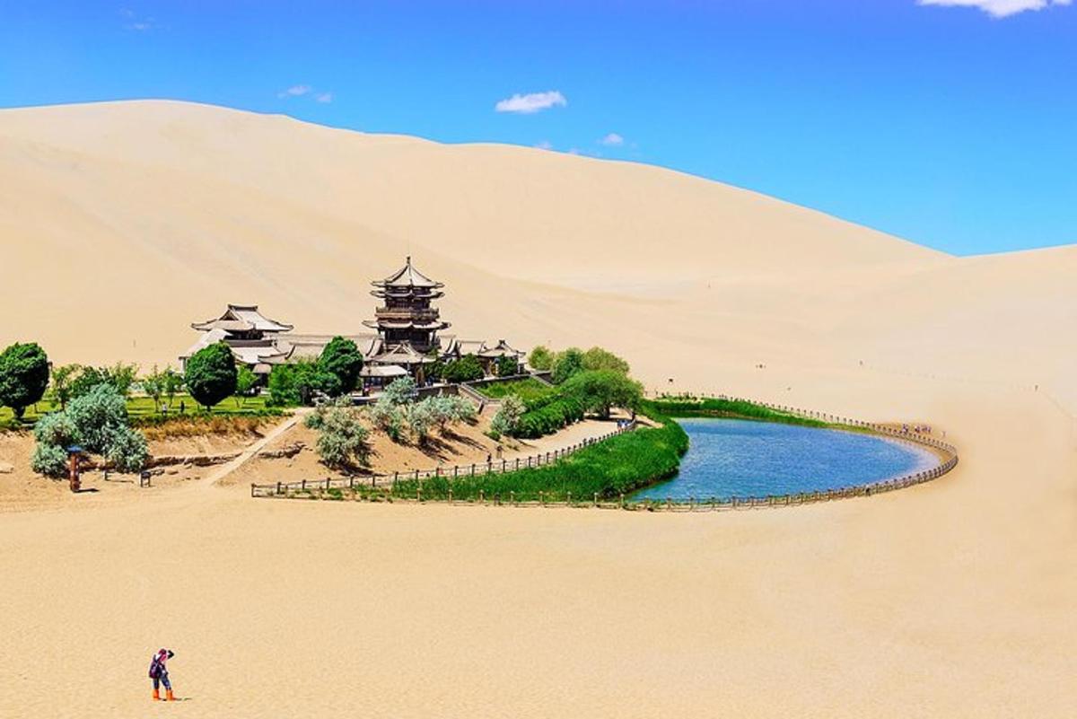 Una persona parada en la arena cerca de un río en el desierto.